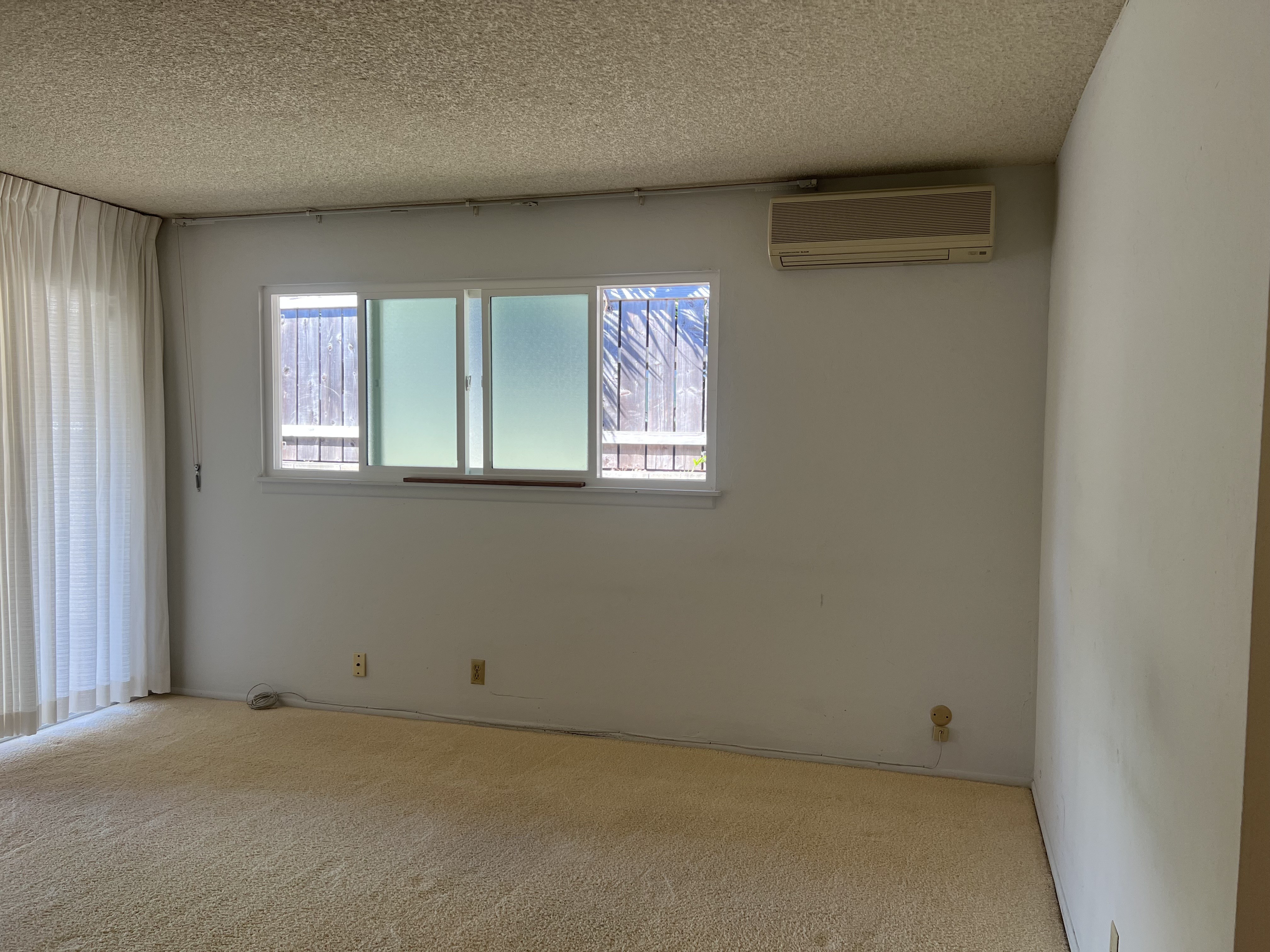 A room with a window and a carpet on the floor.